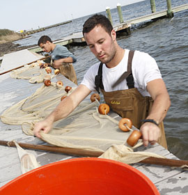 Environmental science students at Barnegat Bay inspect netting on a dock. Credit: Robin Miller Photography